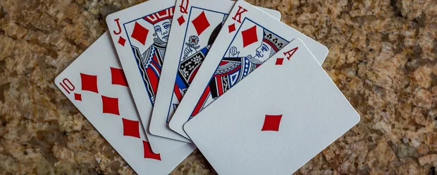 Spillekort med en royal flush i ruder på en stenoverflade